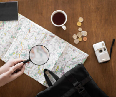 Flat lay, travel planning, trip, map and magnifying glass in female hands.