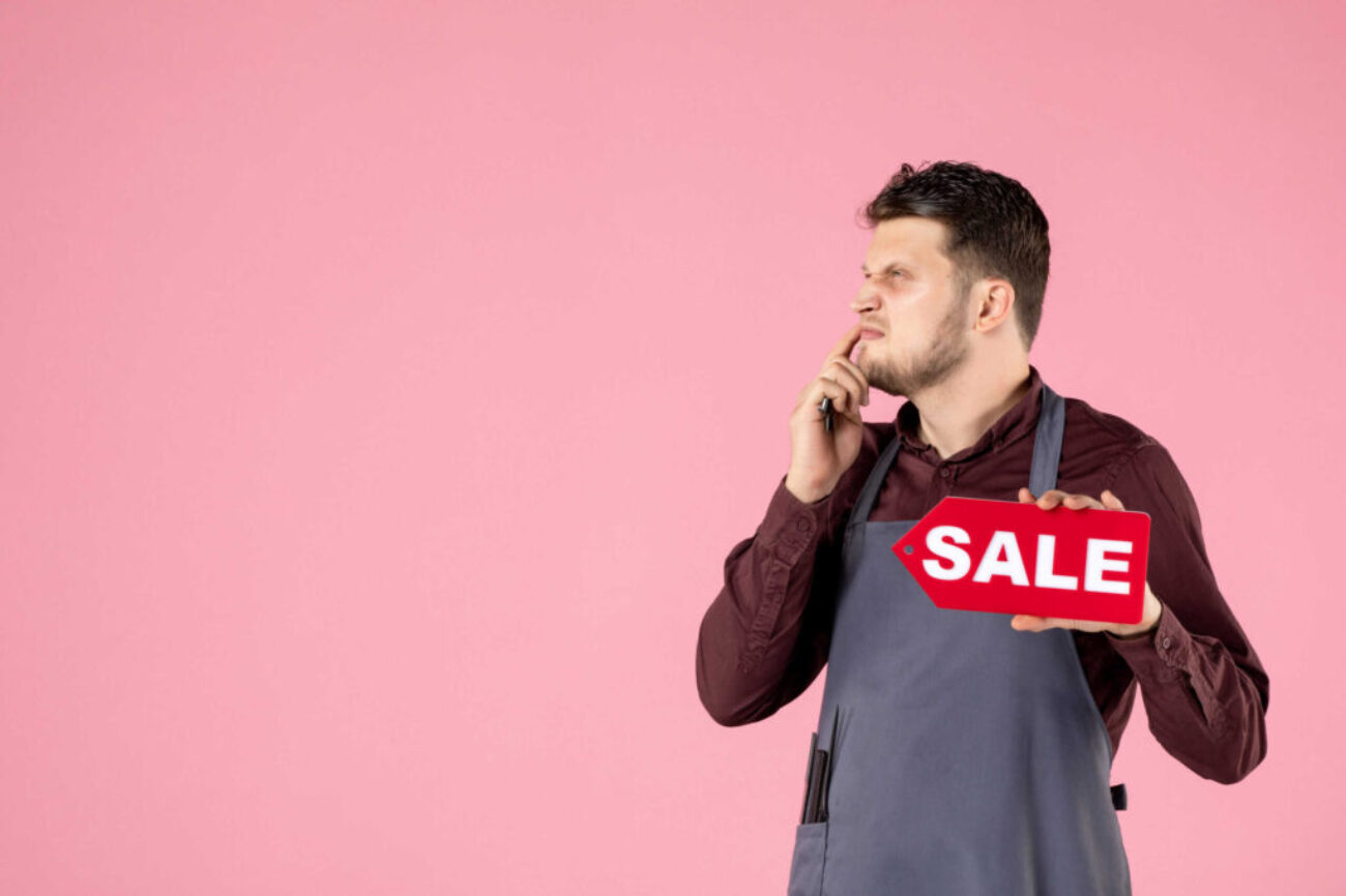 front-view-male-hairdresser-with-sale-nameplate-scissors-pink-background