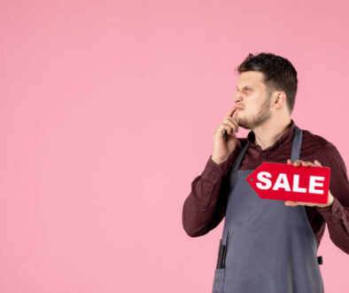 front-view-male-hairdresser-with-sale-nameplate-scissors-pink-background