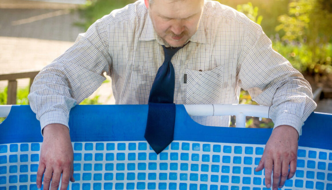 A handsome man in a business suit is suffering from the heat by