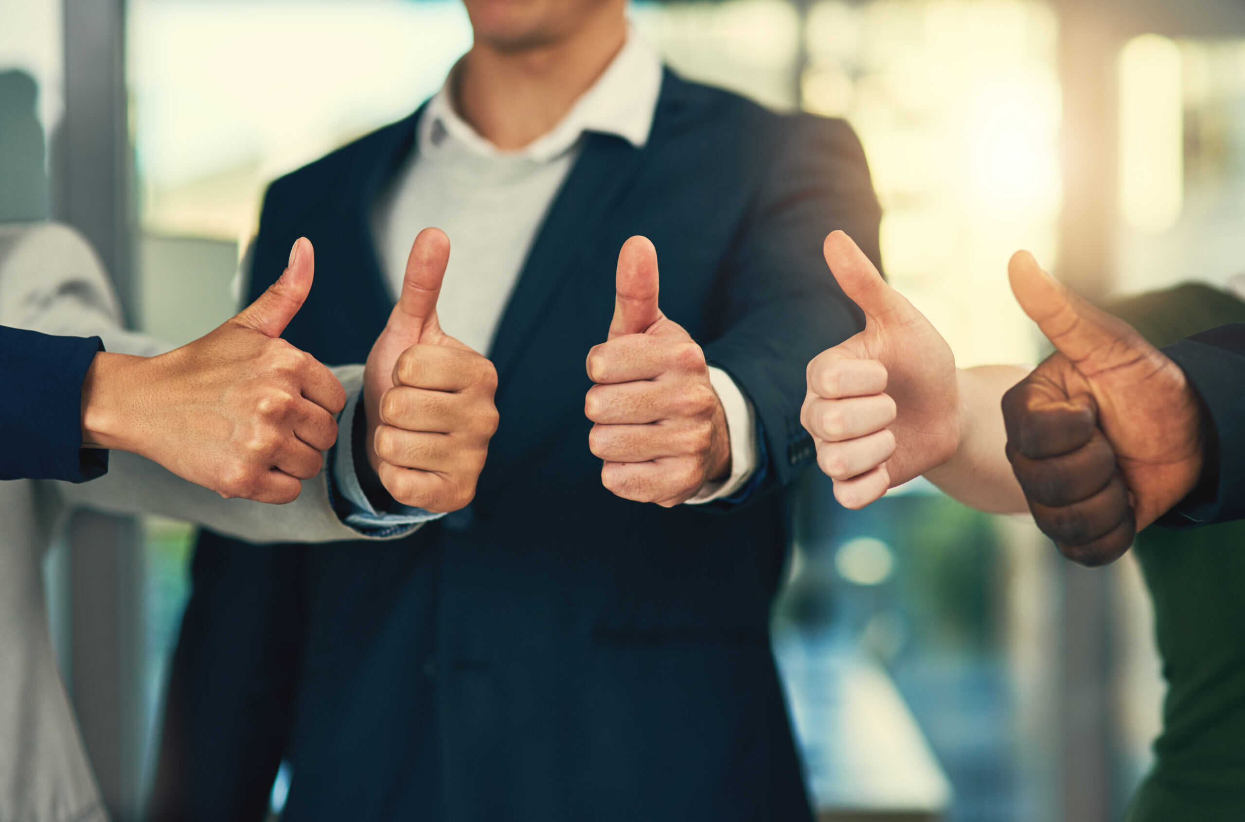 Youre our most valued employee. Cropped shot of a group of businesspeople giving thumbs up in a modern office.