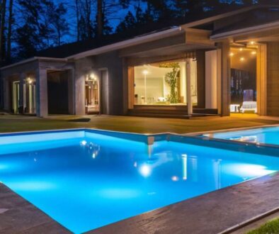 Night view of a beautiful white house with solar panels and a swimming pool