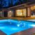 Night view of a beautiful white house with solar panels and a swimming pool