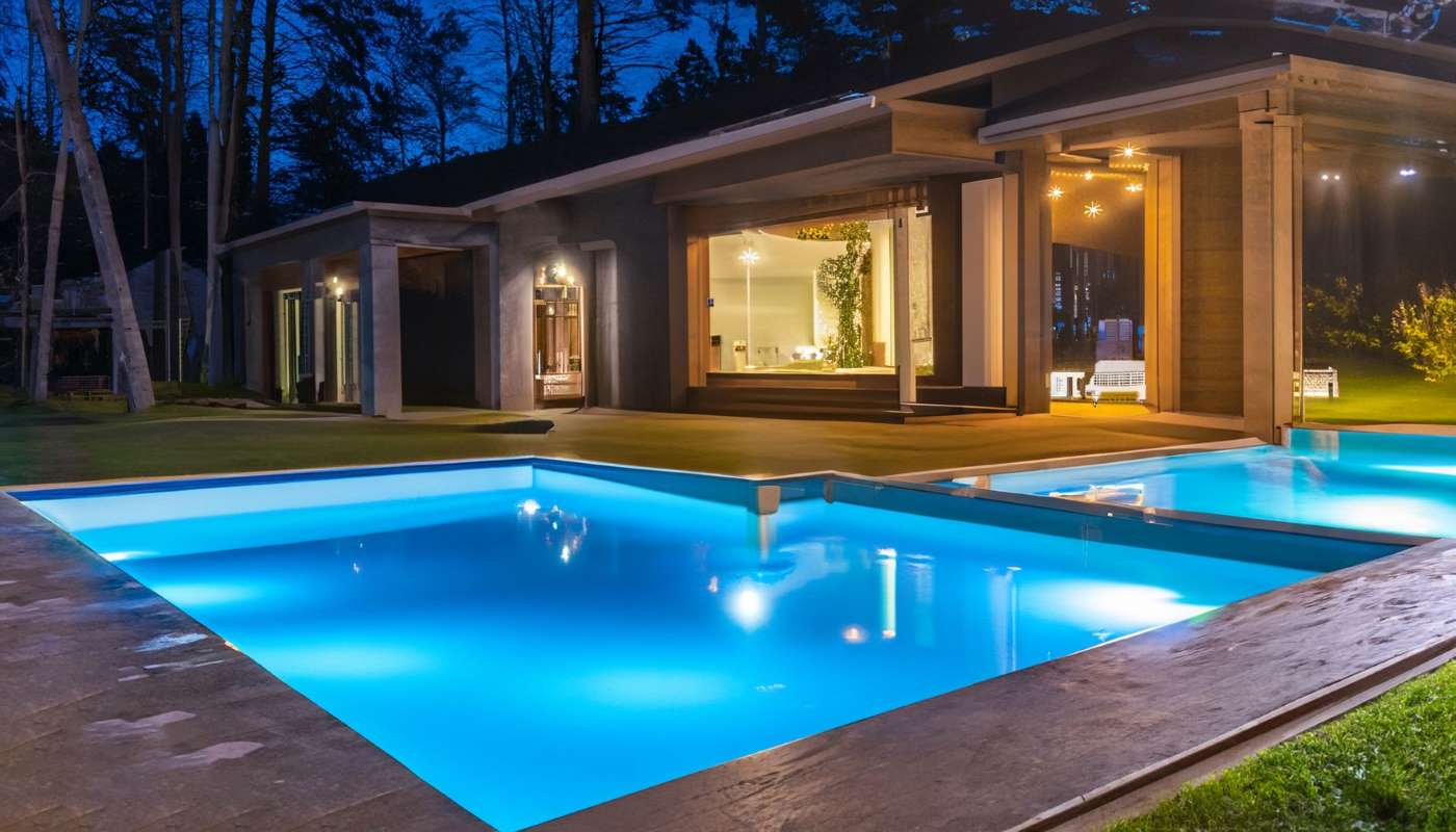 Night view of a beautiful white house with solar panels and a swimming pool