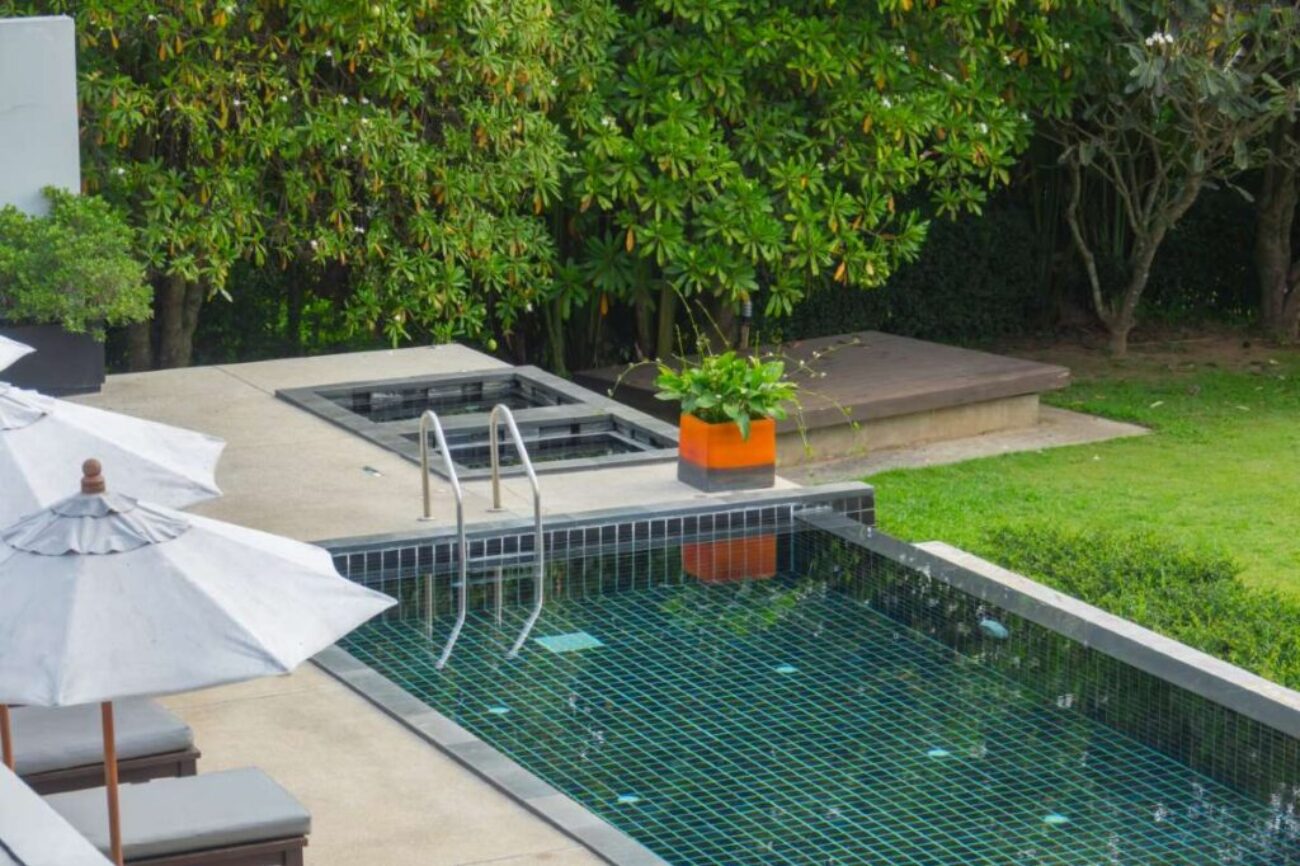 Swimming pool with metal stair with green nature backgroun