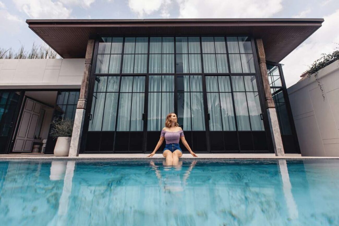 adorable-lovely-young-model-wearing-colored-jacket-shorts-is-sitting-by-pool-with-clear-water-against-background-large-house-rich-life-concept_0x800