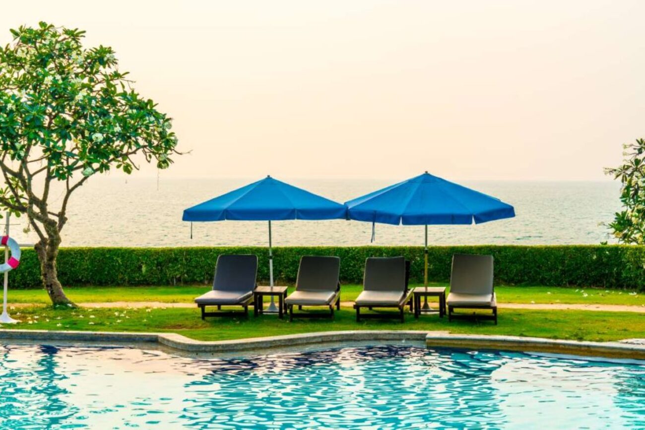 beach-chair-pool-bed-with-umbrella-around-swimming-pool-with-sunset-sea_0x800