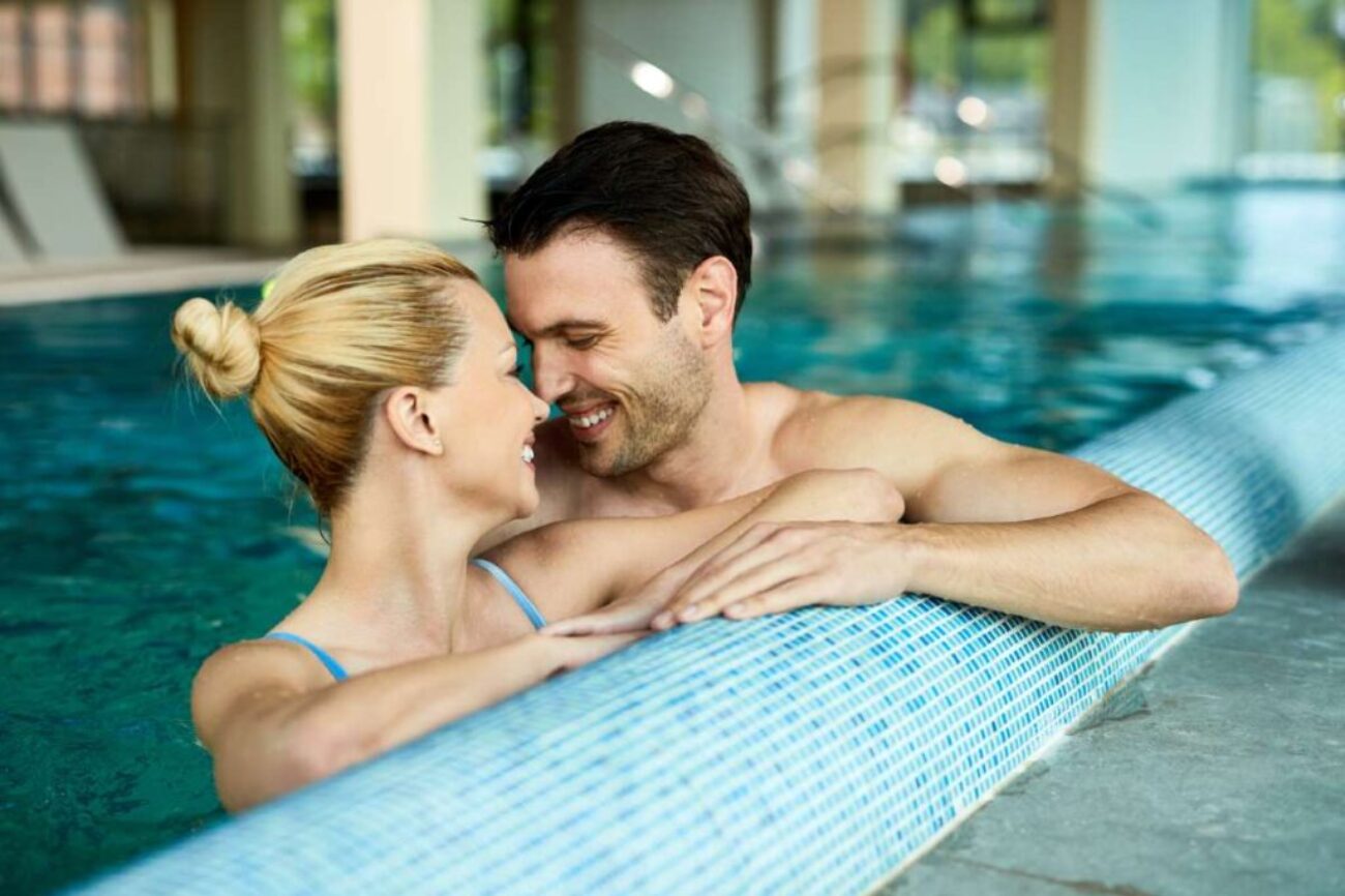 loving-couple-talking-face-face-while-being-water-indoor-swimming-pool-spa_0x800