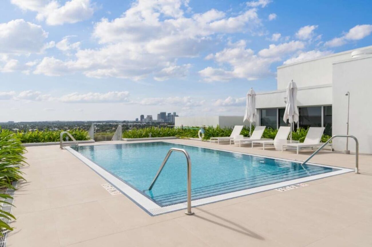 modern-building-with-swimming-pool-trees-chairs-urban-landscape-with-blue-sky-reflecting-pool(1)_0x800