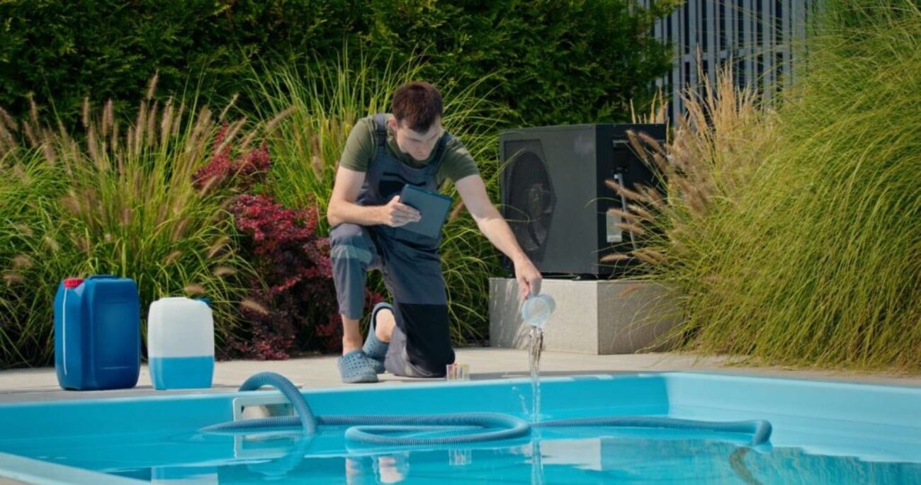 pool-technician-pouring-liquid-into-pool-while-using-tablet-surrounded-by-chemical-containers_0x800