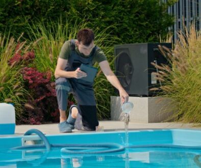 pool-technician-pouring-liquid-into-pool-while-using-tablet-surrounded-by-chemical-containers_0x800