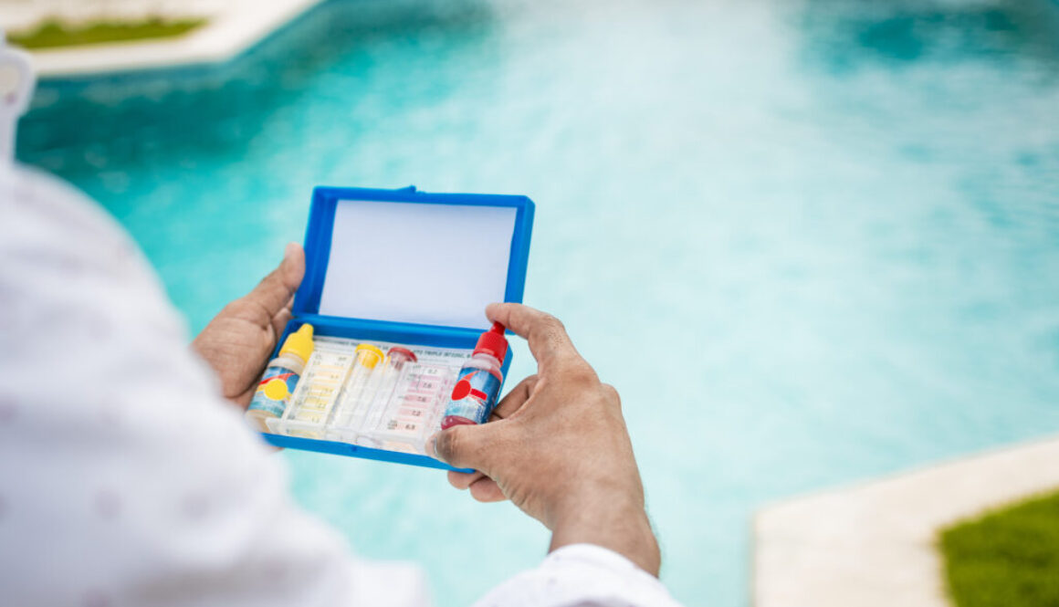 Hand holding Water Test Kit on blurred pool background, Hand holding a pool ph and chlorine tester, Person holding complete water test kit with blurred pool background