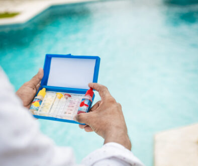 Hand holding Water Test Kit on blurred pool background, Hand holding a pool ph and chlorine tester, Person holding complete water test kit with blurred pool background