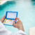 Hand holding Water Test Kit on blurred pool background, Hand holding a pool ph and chlorine tester, Person holding complete water test kit with blurred pool background