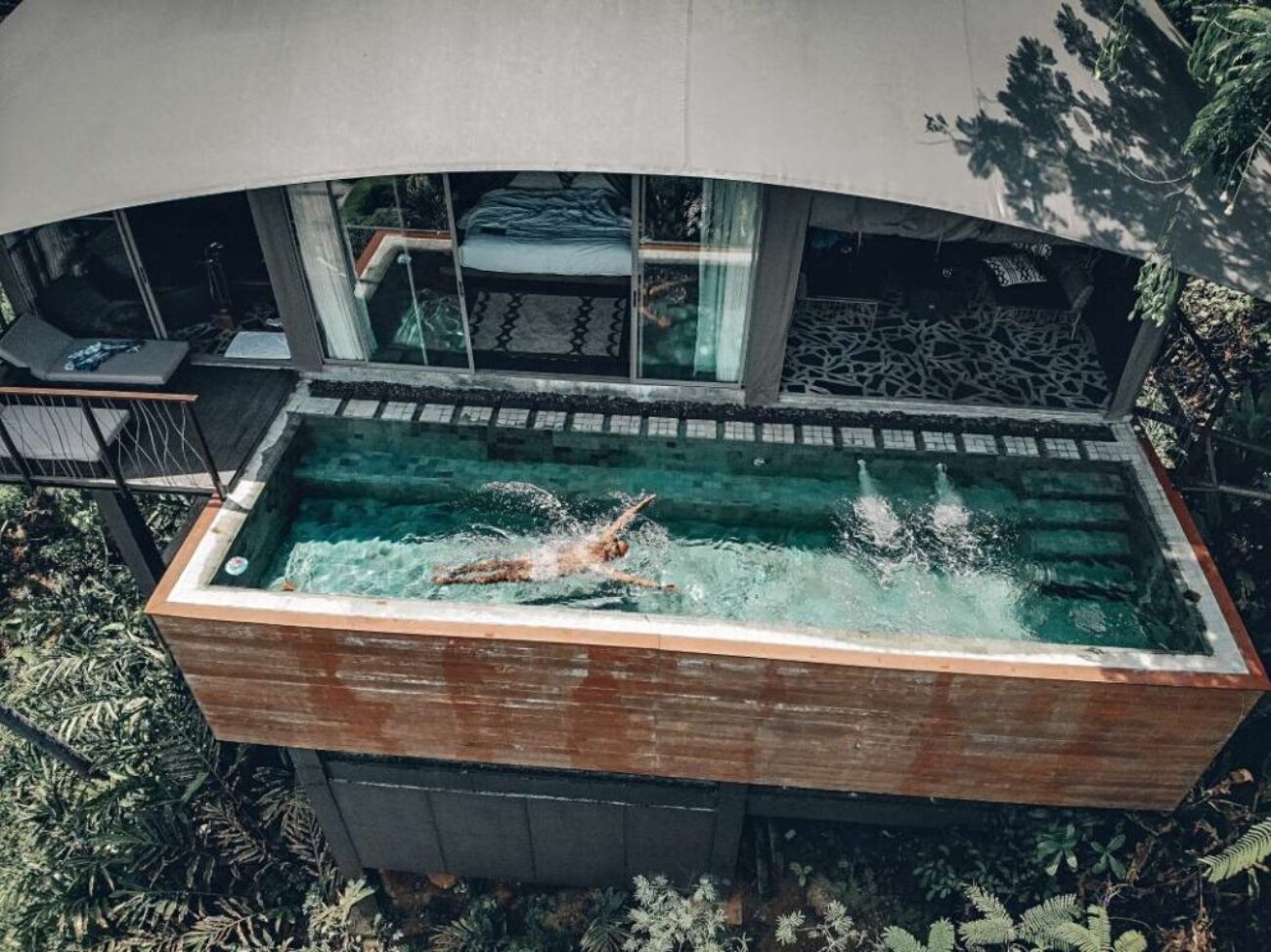 aerial-view-fit-male-swimming-clear-pool-that-is-balcony-hotel-palms-around-arched-grey-roof-recreation-concept_0x800