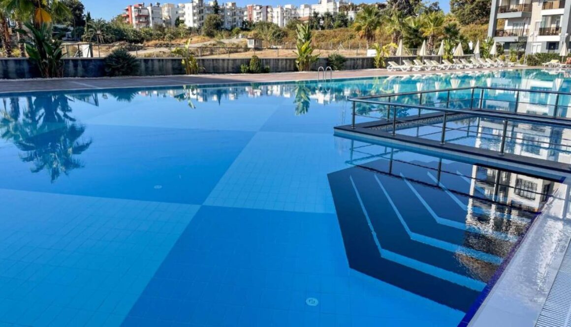 large-outdoor-swimming-pool-with-modern-glass-railings-serene-view-surrounding-greenery_0x800