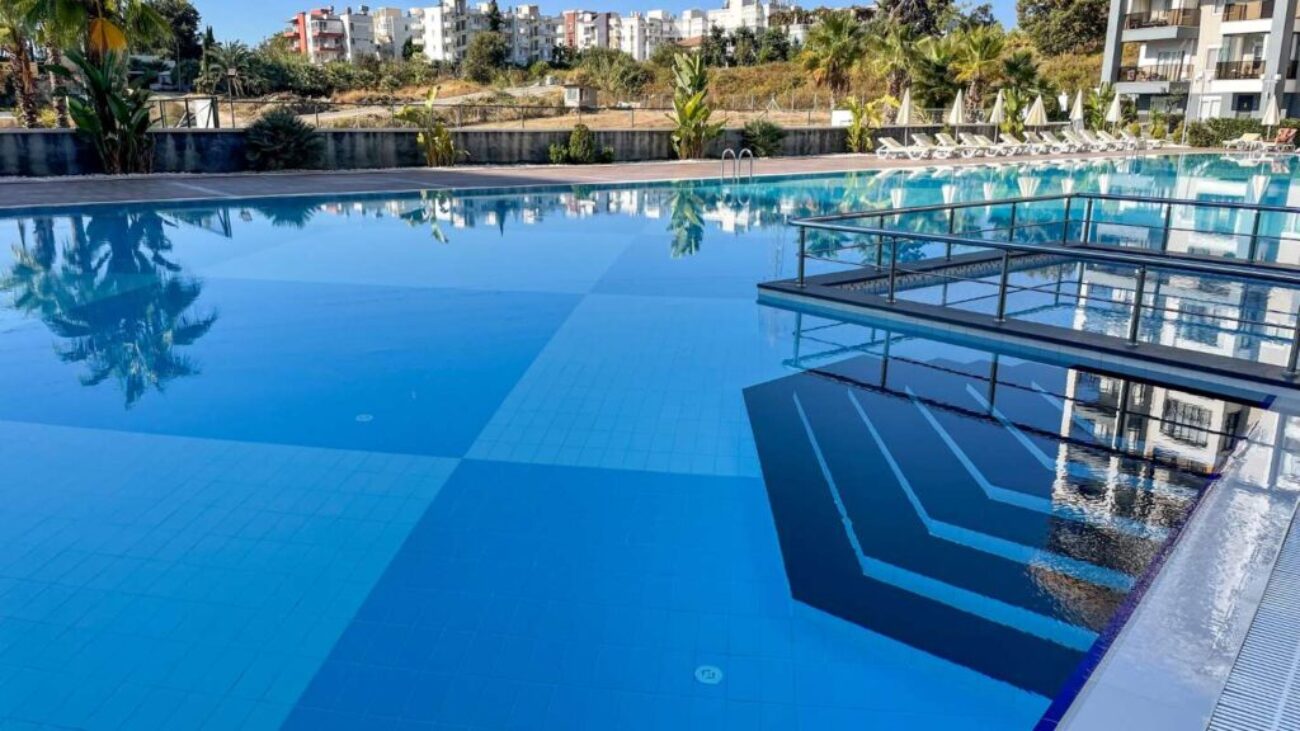 large-outdoor-swimming-pool-with-modern-glass-railings-serene-view-surrounding-greenery_0x800