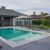 wooden-lounge-chairs-modern-villa-pool-deck-light-blue-water-swimming-pool-luxurious-mansion-with-chairs-around-it-modern-house-background_0x800